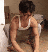 a man wearing glasses is squatting on the floor