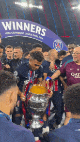 a group of soccer players holding a trophy in front of a sign that says winners