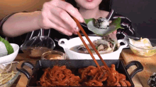 a woman is eating food with chopsticks and a plate of food