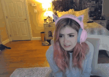 a girl with pink hair wearing a pair of pink cat ears headphones