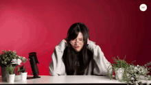 a woman wearing a sweatshirt that says levis sits at a desk in front of a red background