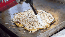 a pizza is being cooked on a griddle with the words made in animotica visible