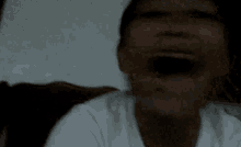 a close up of a person 's face with their eyes closed and a white shirt on .
