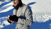 a man wearing glasses and a grey jacket stands in the snow