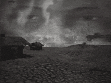 a black and white photo of a landscape with a plane flying in the background