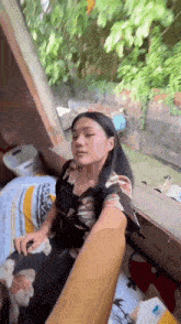 a woman is sitting on a bed with a man 's hand on her shoulder .
