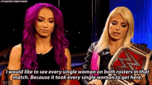 two women are standing next to each other holding a wrestling championship belt and talking .