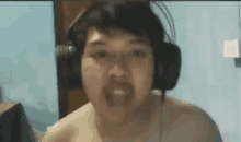 a shirtless man wearing headphones and a beard is making a funny face .
