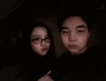 a man and a woman are posing for a picture in a dark room