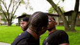 a man with braids on his head kisses another man on the cheek