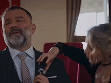 a man in a suit and tie is being touched by a woman in a black shirt