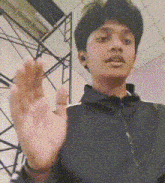 a young man in a black jacket is making a funny face .