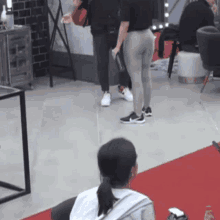 a woman in a white shirt is sitting in a chair in front of a red carpet