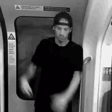 a man wearing a baseball cap is standing in a subway car .