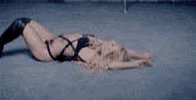 a woman in a black bodysuit is laying on the ground