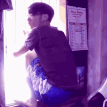 a man sitting in front of a window with a sign that says come eating on the wall behind him