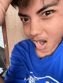 a young man wearing a blue shirt with the word aaa written on it