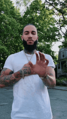 a man with a beard is wearing a white shirt and a gold chain