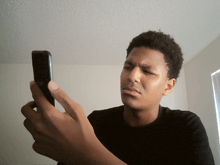 a young man in a black shirt looks at his phone
