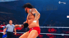 a man in a red shorts is wrestling in a ring .