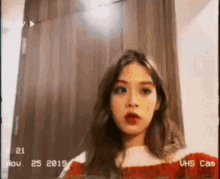 a woman in a red dress is taking a selfie in front of a wooden door .