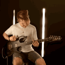 a man is playing a kiesel electric guitar in a dark room