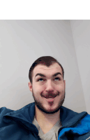 a man with a beard wearing a blue jacket makes a funny face