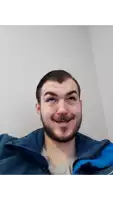 a man with a beard wearing a blue jacket makes a funny face