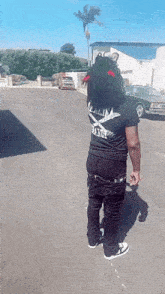 a man wearing a black shirt and black pants is standing on the side of the road .