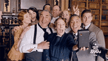 a group of people taking a selfie with a sign that says " text santa "