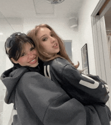 two girls posing for a picture with one wearing a black jacket with the letter u on it