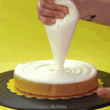 a person frosting a cake with a bag that says mr.cakes on the bottom
