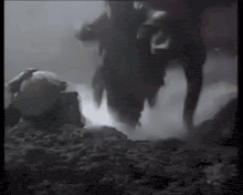 a person is standing on a rock in a dark room with smoke coming out of it .