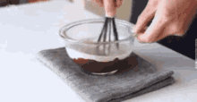 a person is whisking a mixture in a glass bowl .
