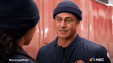 a man in a chicago fire jacket talks to a woman in a beanie