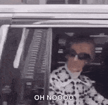 a woman is sitting in a car wearing sunglasses and a cow print jacket .
