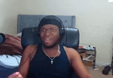 a man wearing headphones and a necklace with a cross on it is sitting in a chair .