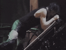 a man in a black tank top is sitting in a dark room