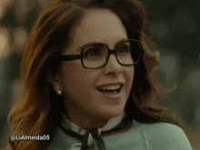 a woman wearing glasses and a scarf is smiling with the hashtag lialmeida05