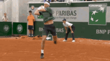 a tennis player swings his racket in front of a bnp paribas ad