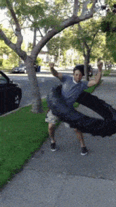 a man is standing on a sidewalk holding a tire in his hands
