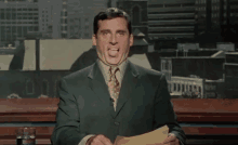 a man in a suit and tie is sticking out his tongue while holding a piece of paper