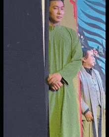 a man in a green robe stands next to another man in a white coat