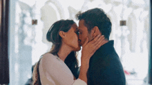 a man and a woman are kissing each other in front of a window