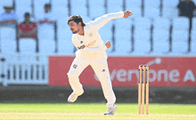 a man in a white jersey with emirates written on it throws a ball