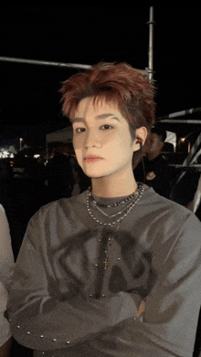 a young man with red hair is wearing a necklace with a cross