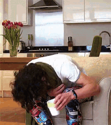 a man is sitting on a couch with his head down and a cup of coffee in his hand