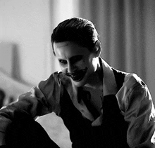 a black and white photo of a man dressed as the joker with his mouth open .