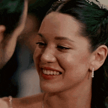 a close up of a woman wearing a tiara and earrings smiling