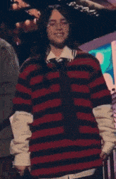 a woman wearing a red and black striped sweater smiles with her eyes closed
